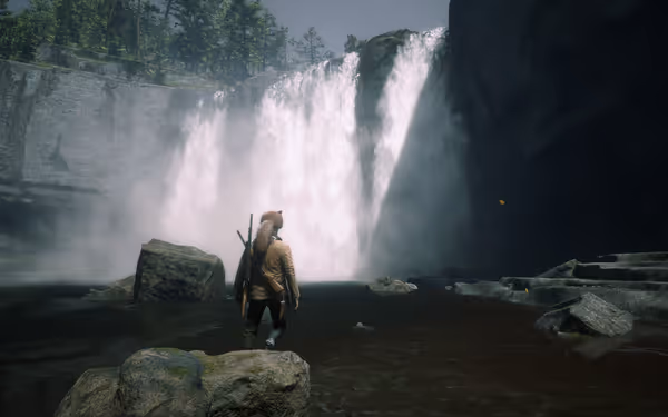 Person standing in water near waterfall, rocks, trees in background.