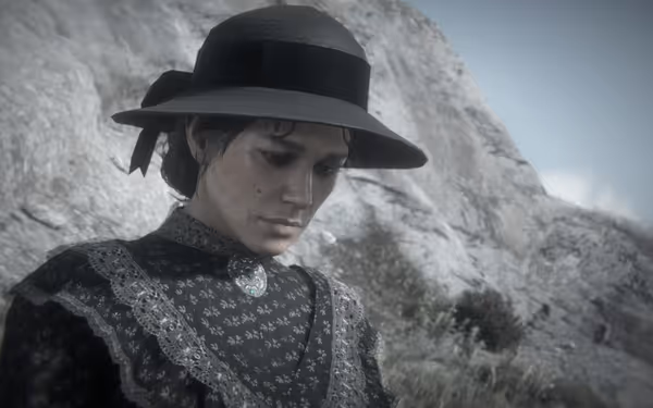 A woman in a dark Victorian-style dress and hat looks down solemnly near rocks.