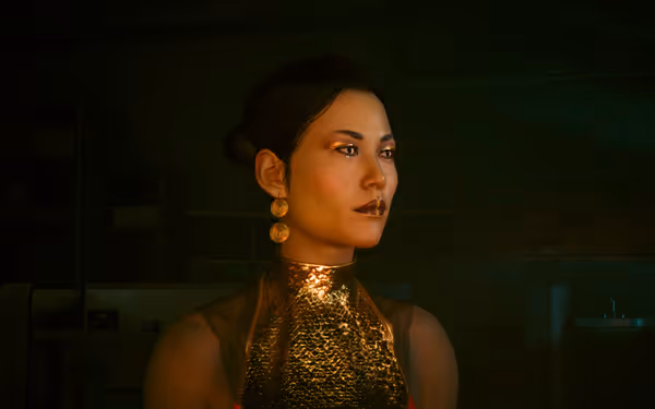 A woman with gold earrings and metallic dress looks ahead in dim indoor lighting.