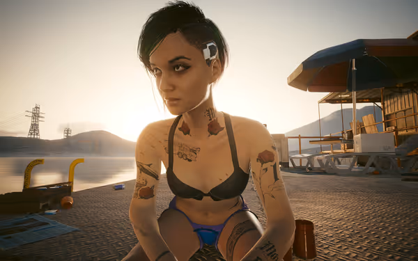 Woman with cybernetic implant and tattoos sits on dock at sunset near beach shack.
