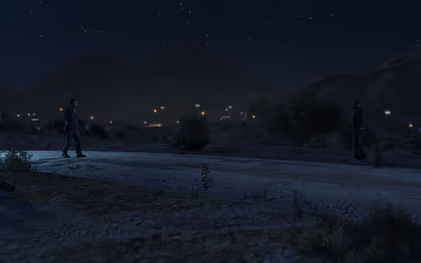 Two men stand on a rural dirt road at night with mountains and city lights behind.